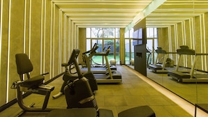 Un gimnasio con cintas de correr, elípticas y bicicletas estáticas, con un diseño moderno, grandes ventanales y vistas al exterior.