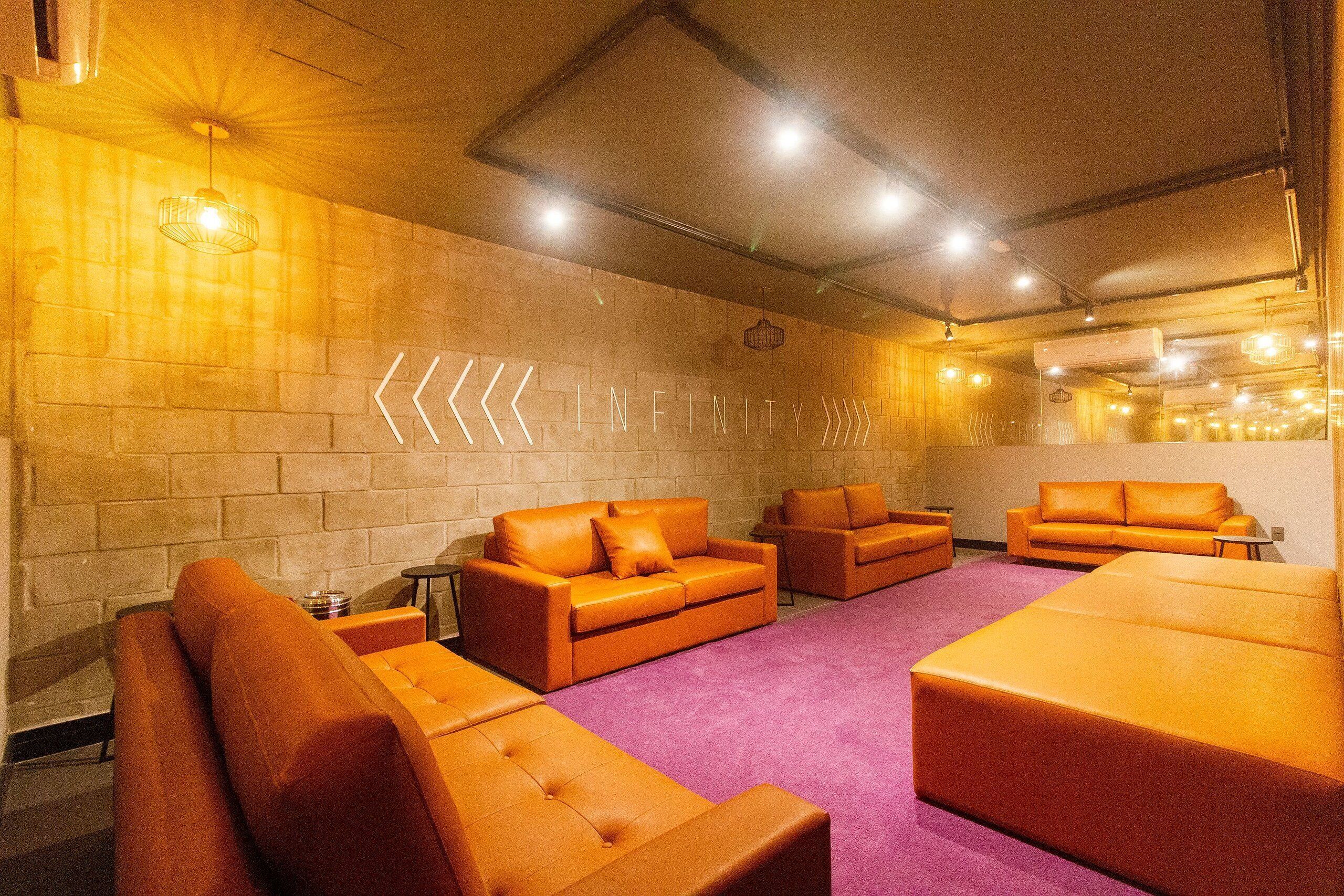 A modern lounge area with orange sofas and a purple carpet.