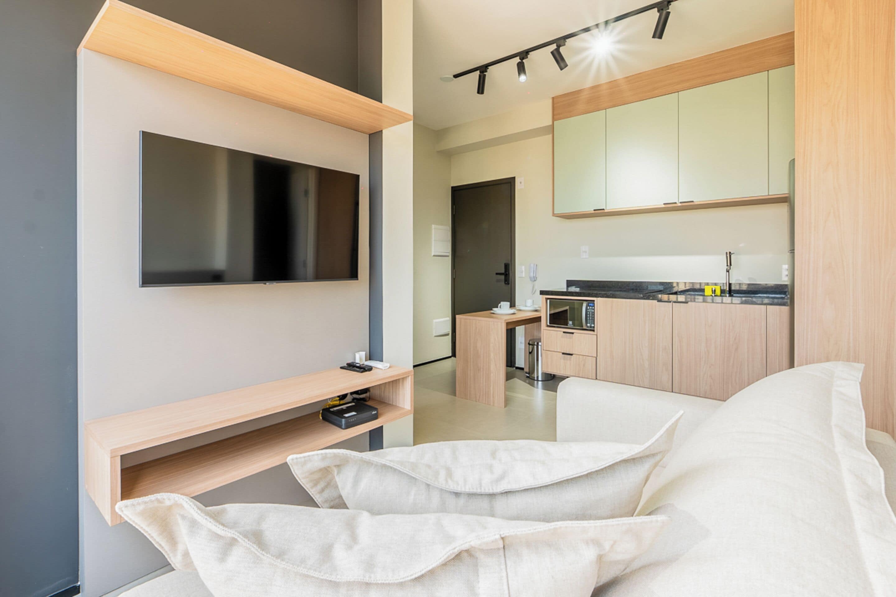 Een moderne woonkamer met een flatscreen televisie, een houten plank en een witte bank.
