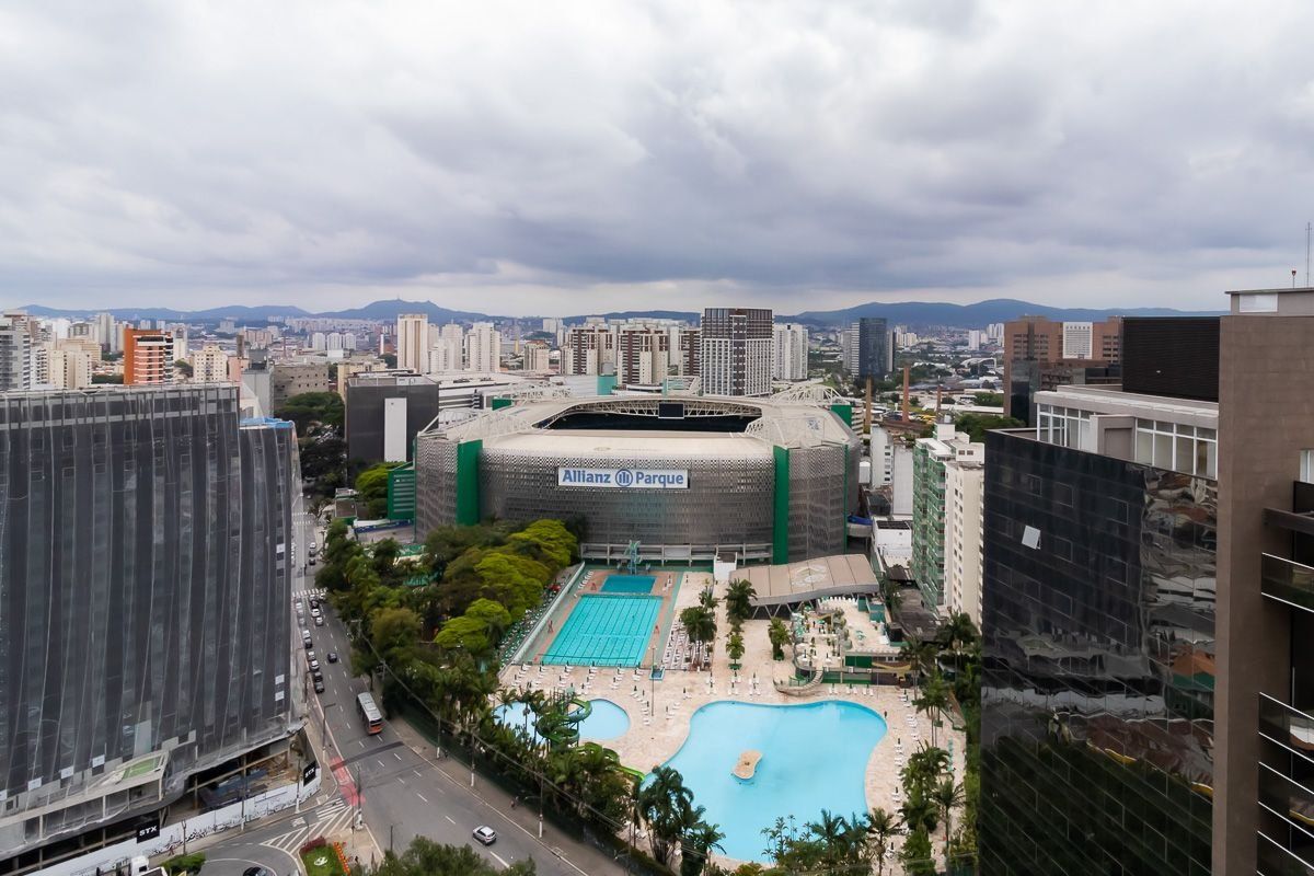 A large building with a swimming pool and a tennis court, surrounded by other buildings.
