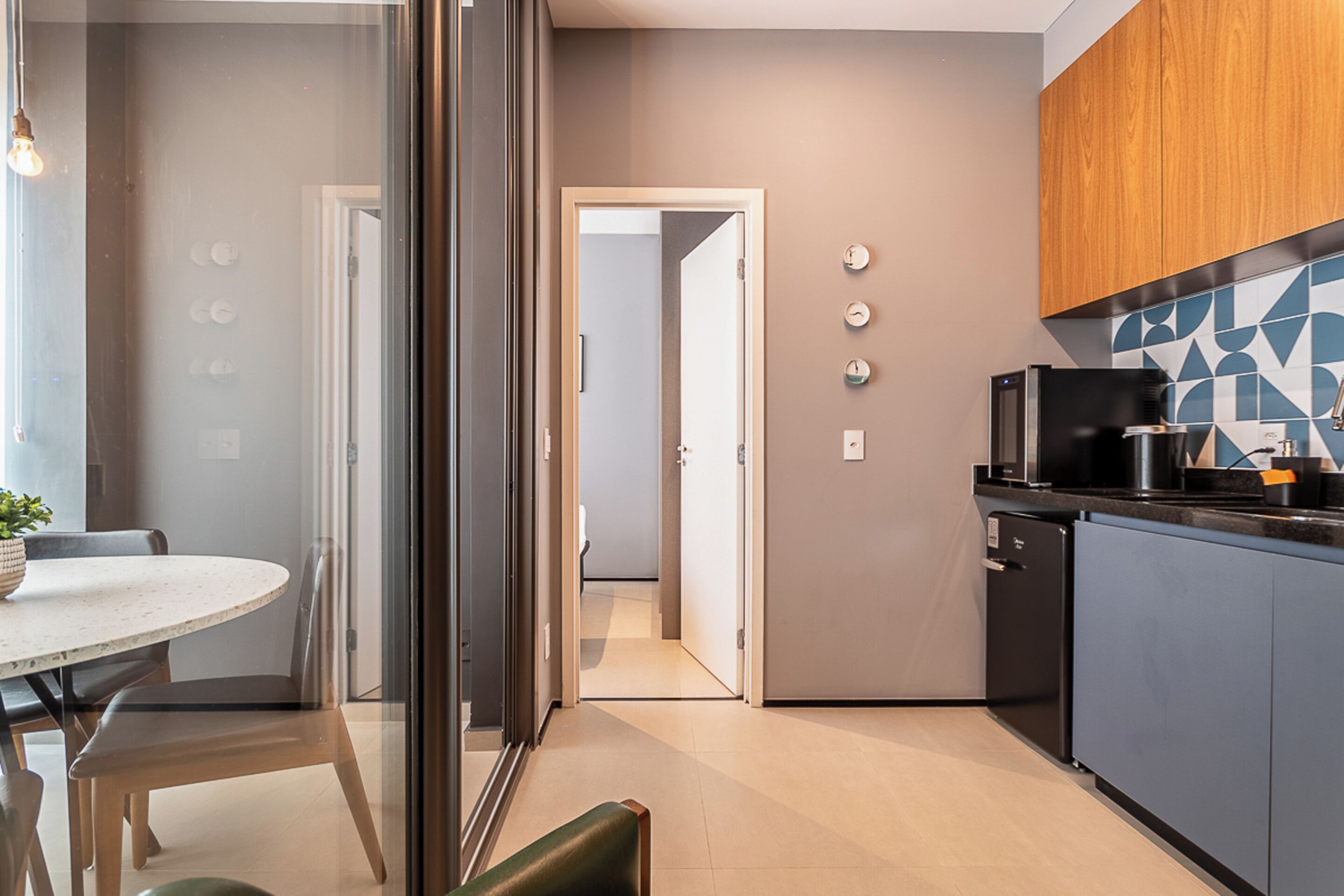 A modern kitchen with a microwave, coffee maker, and a small refrigerator. There is a dining area with a table and chairs.