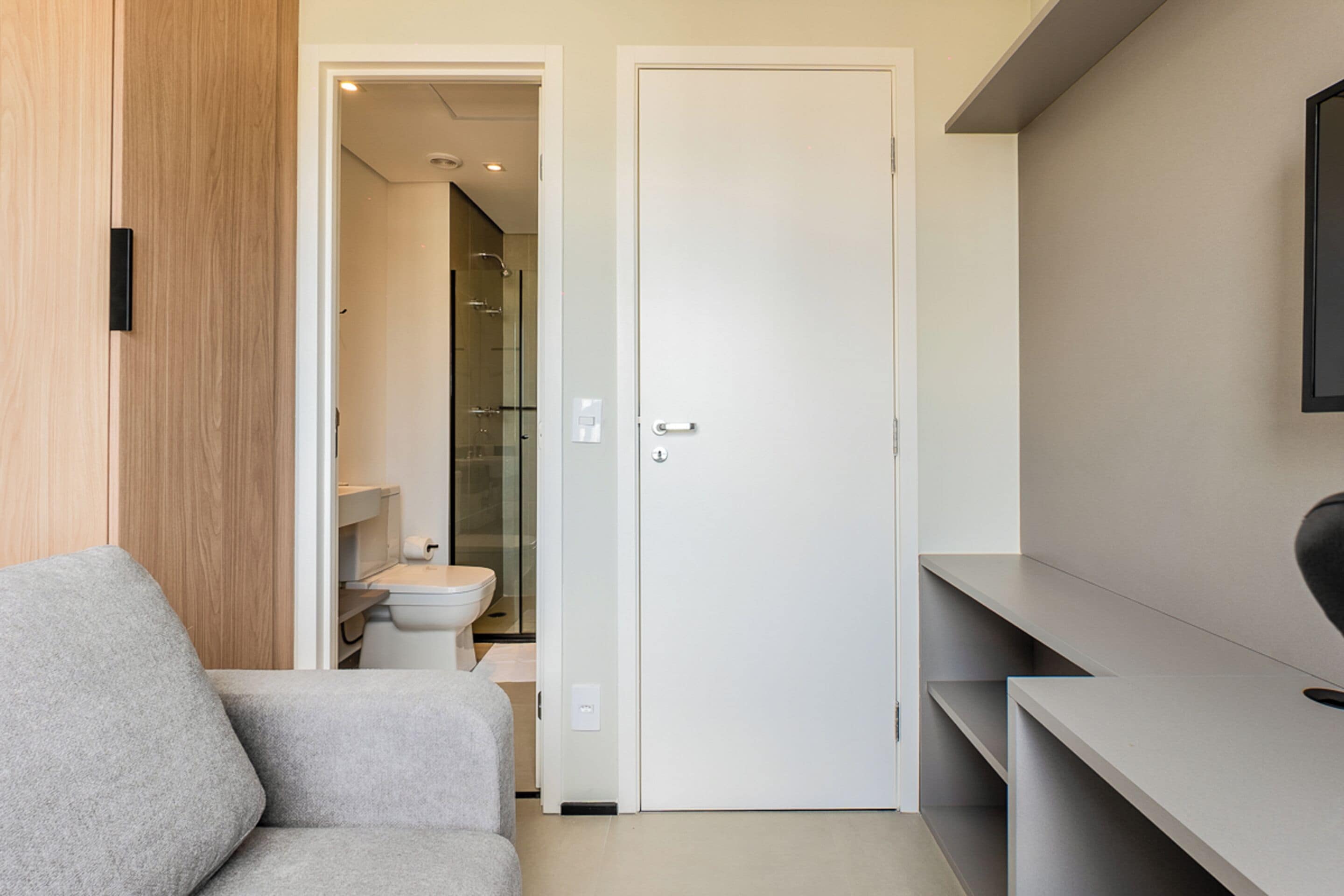 Un baño moderno con cabina de ducha de vidrio, inodoro y puerta blanca.