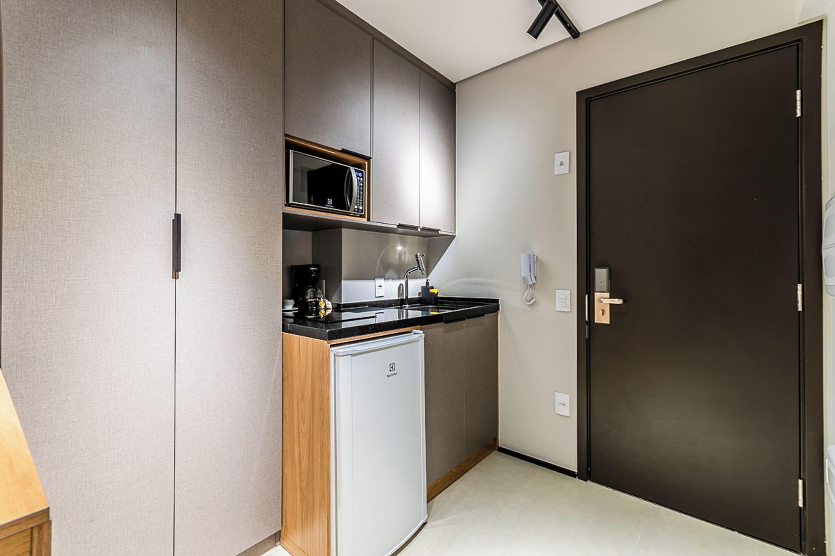 Eine kleine Küche mit Mikrowelle, Spüle und Kühlschrank.