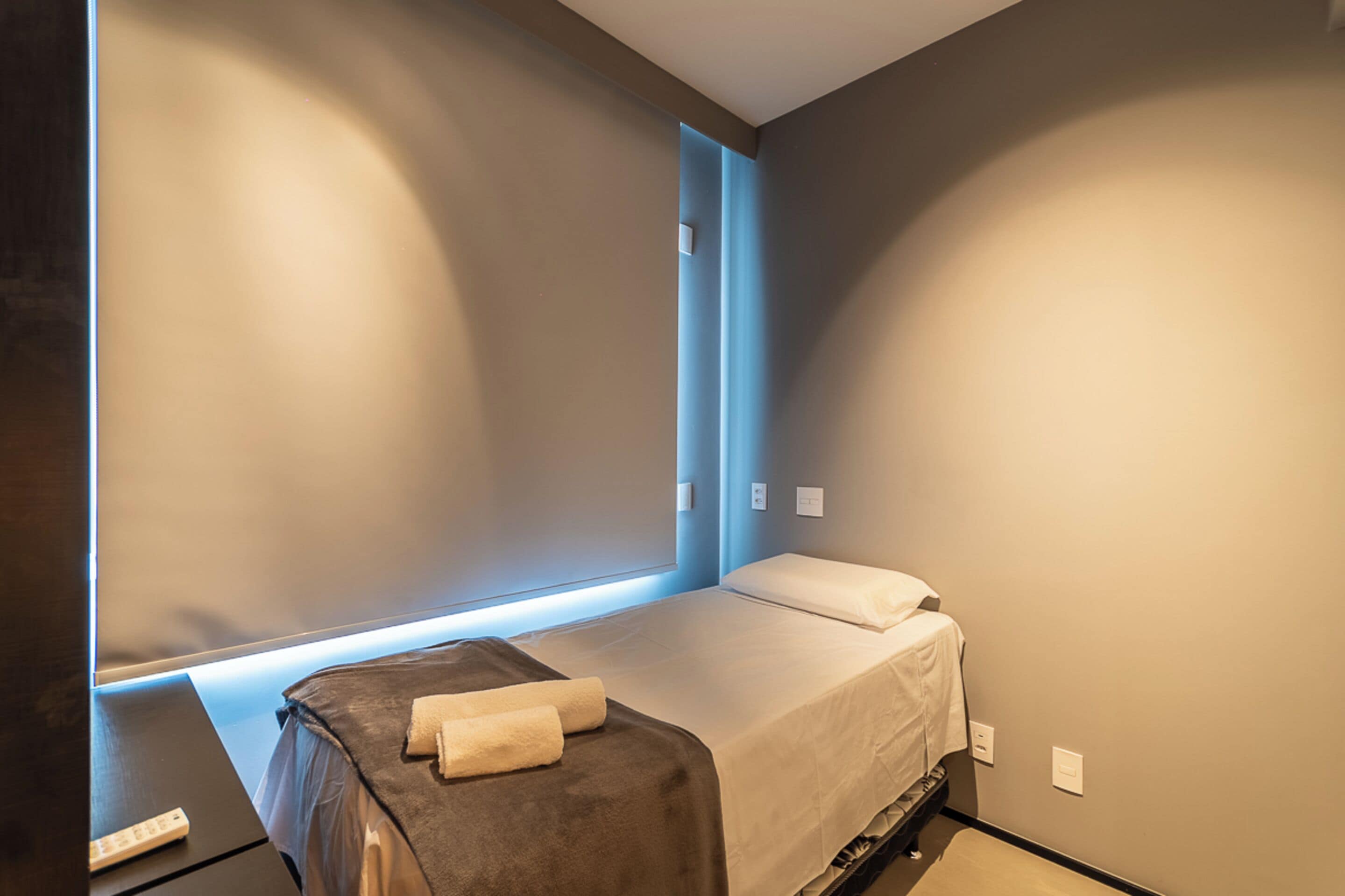 Habitación de hotel moderna con una cama individual, una mesita de noche y ventana con vistas.