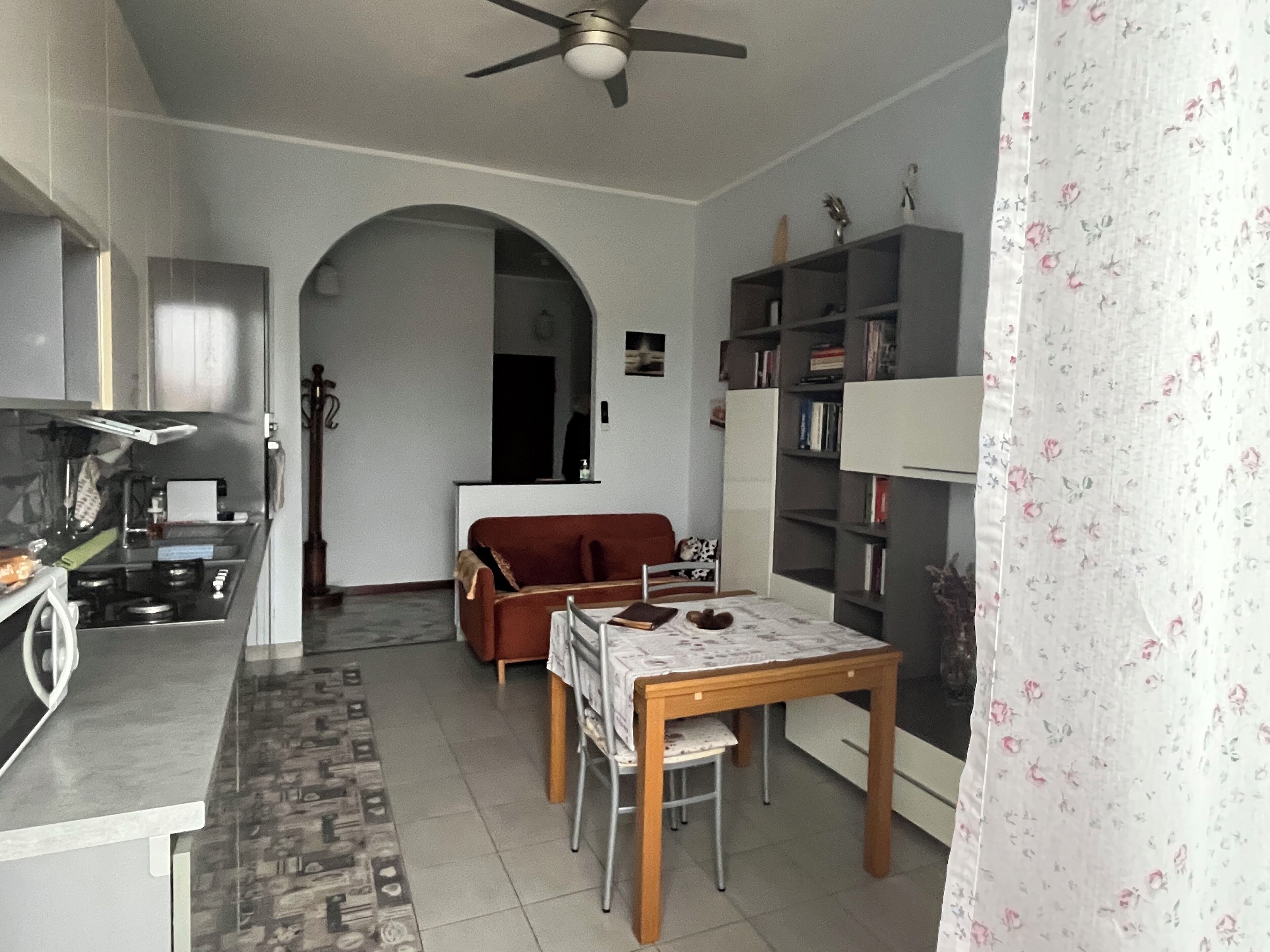 A compact living space with a kitchenette, a dining area, and a bookshelf.