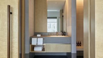 A modern bathroom with a large mirror, a sink with two faucets, and a towel rack.