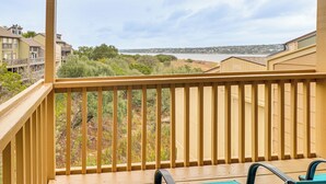 Un balcone in legno con vista su una zona residenziale e un corpo d'acqua.