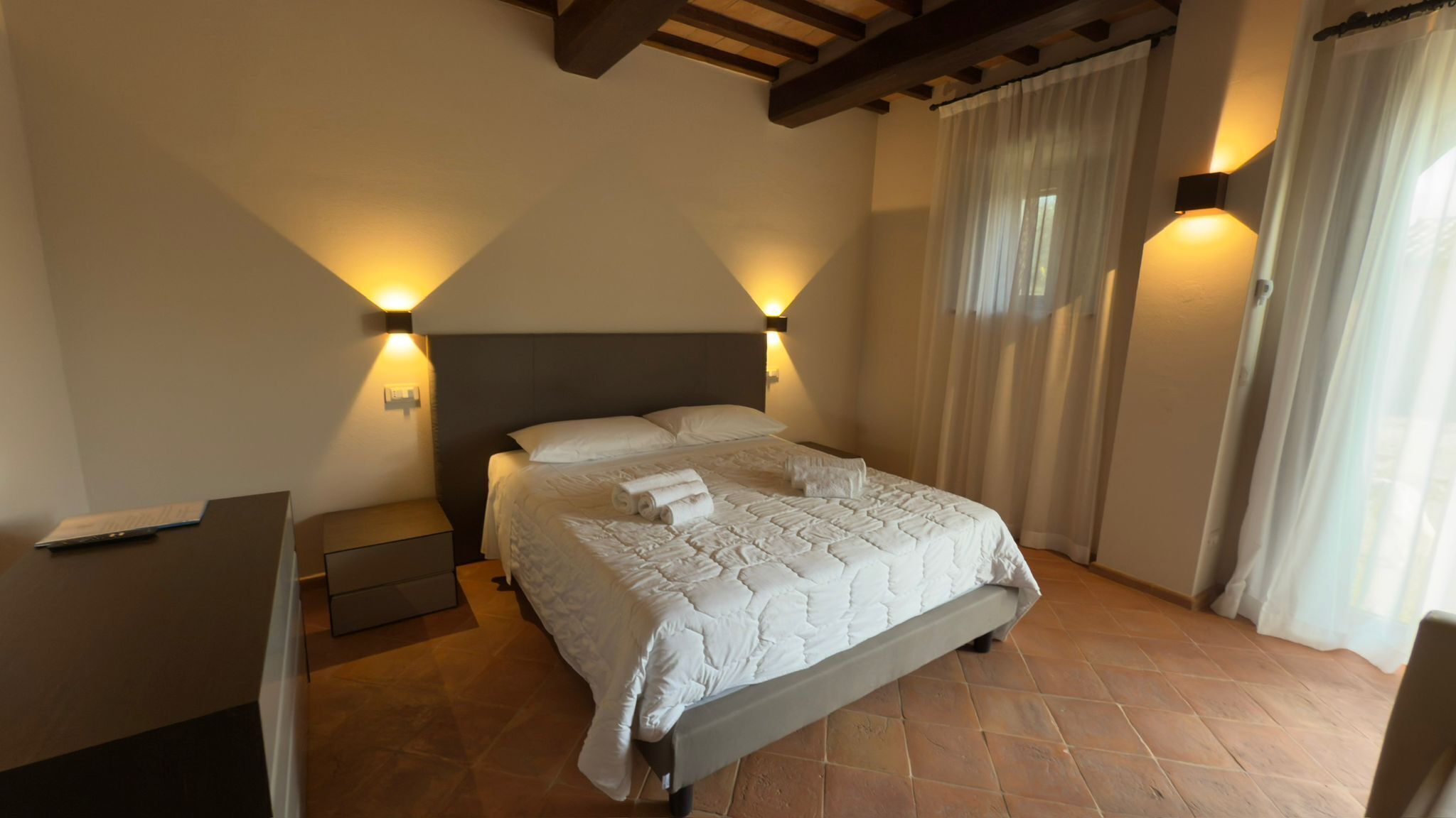 A bedroom with a bed, nightstands, and a desk.