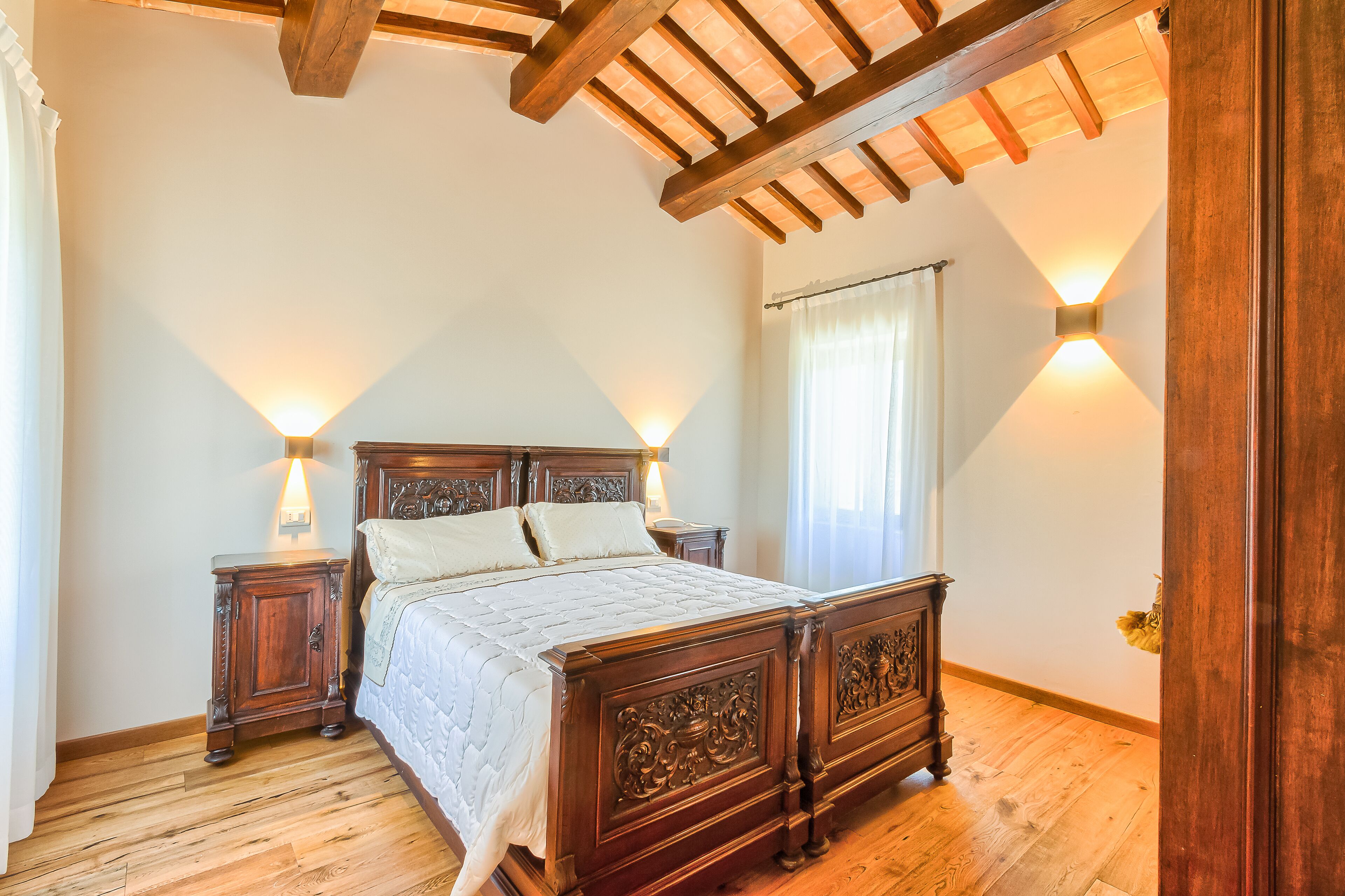 Un dormitorio con una cama de madera, mesitas de noche y apliques de pared.
