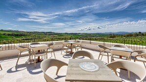 Una terraza con mobiliario exterior y una vista panorámica de campos verdes y montañas.