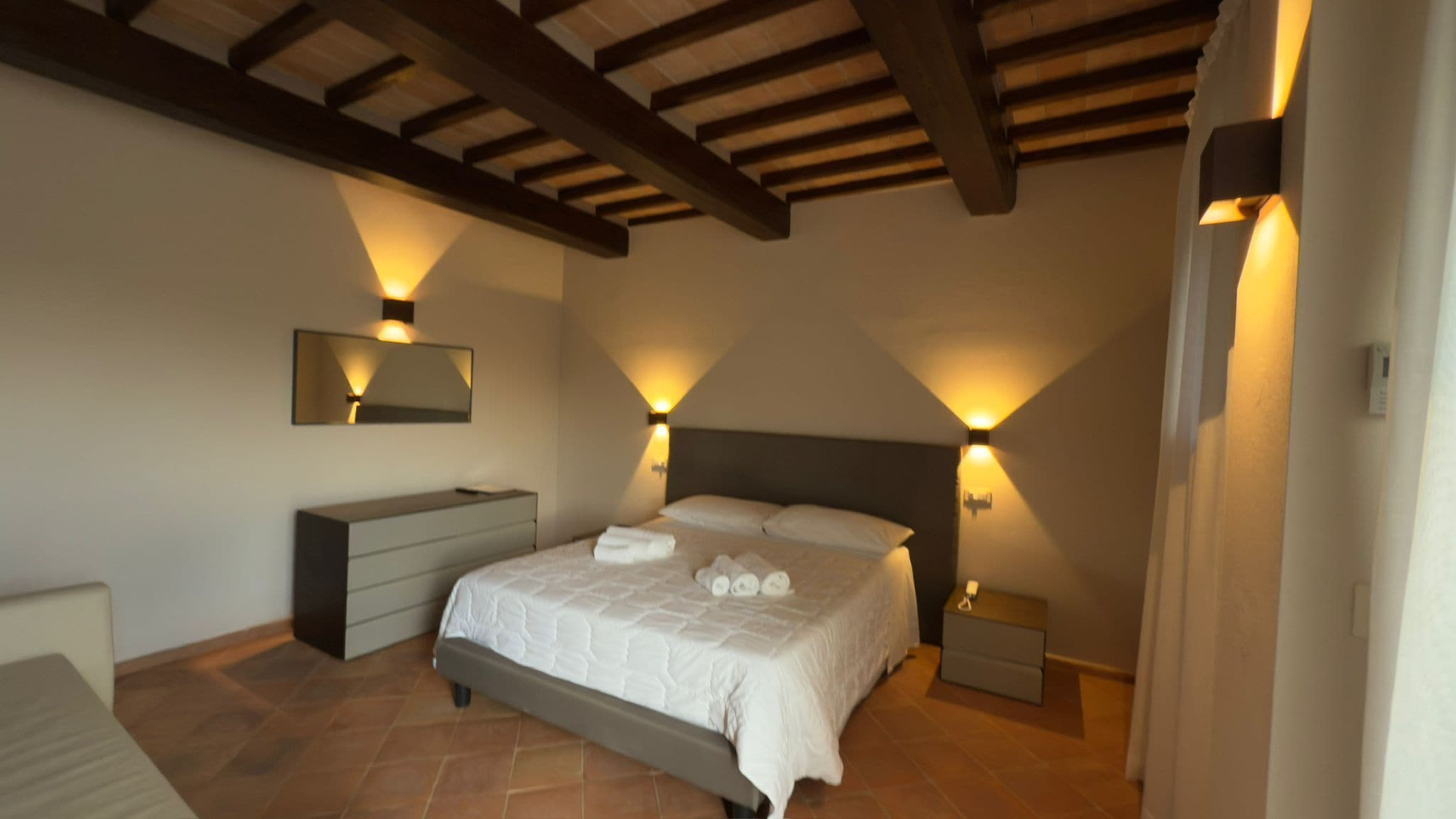 A bedroom with a bed, bedside tables, a dresser, and a mirror.