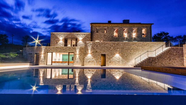 Un edificio de piedra con una piscina al frente.