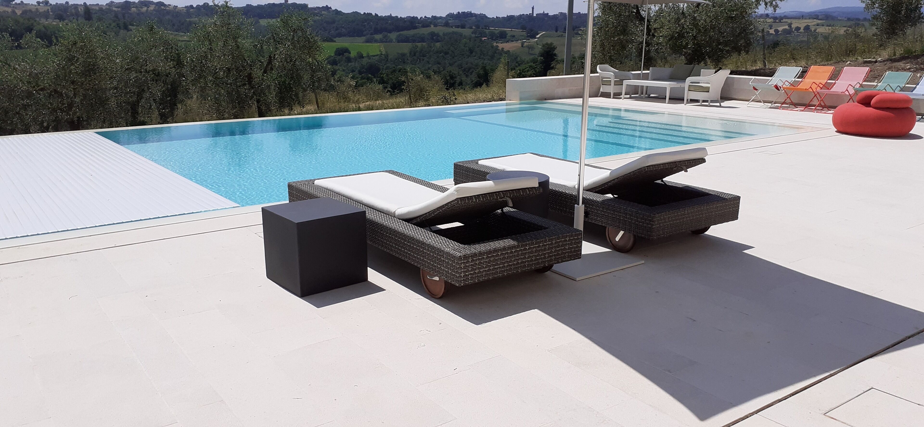 Ein moderner Poolbereich im Freien mit Liegestühlen und einem Lautsprecher.