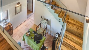 Un interior moderno con techo de madera, una escalera de cristal y un comedor con mesa y sillas.