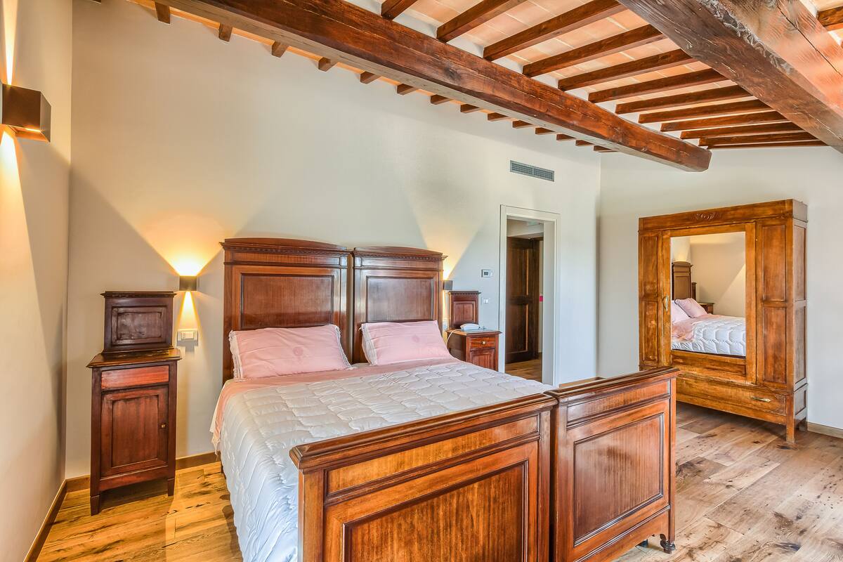 Un dormitorio con una cama de madera, mesitas de noche y un espejo grande.
