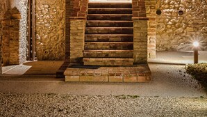 Un edificio de piedra con puerta de madera, una escalera y dos ventanas.