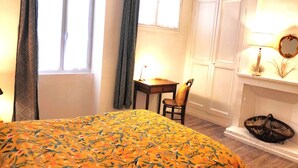 Un dormitorio con cama, escritorio, silla, ventana y lámpara.