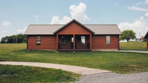 A single-story wooden building with a gabled roof, a front porch, and a gravel driveway.