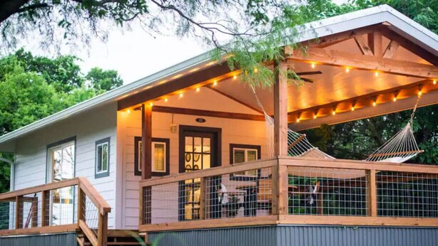Ein Haus mit überdachter Veranda, einer Hängematte und Lichterketten.