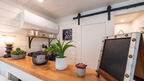 Een goed verlichte kamer met een houten toonbank, planten in potten, een schoolbord en een wandairconditioner.