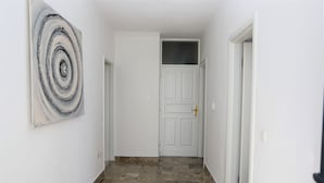 A hallway with a white door, a painting on the wall, and a tiled floor. - Stella Maris Hvar - Sea View Rooms with Balcony (Hvar)