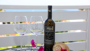 A bottle of wine and two glasses on a table with a tiled surface, surrounded by pink flowers. - Stella Maris Hvar - Sea View Rooms with Balcony (Hvar)