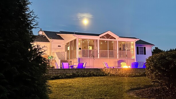 Uma casa com varanda coberta, área de estar externa e um deck bem iluminado.