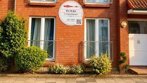A red brick building with a sign indicating it is a vacation rental. - Haus am Mühlenpark Whg. 8, Steinmarnerstr.77/79, 27476 Cuxhaven (Cuxhaven- Döse)
