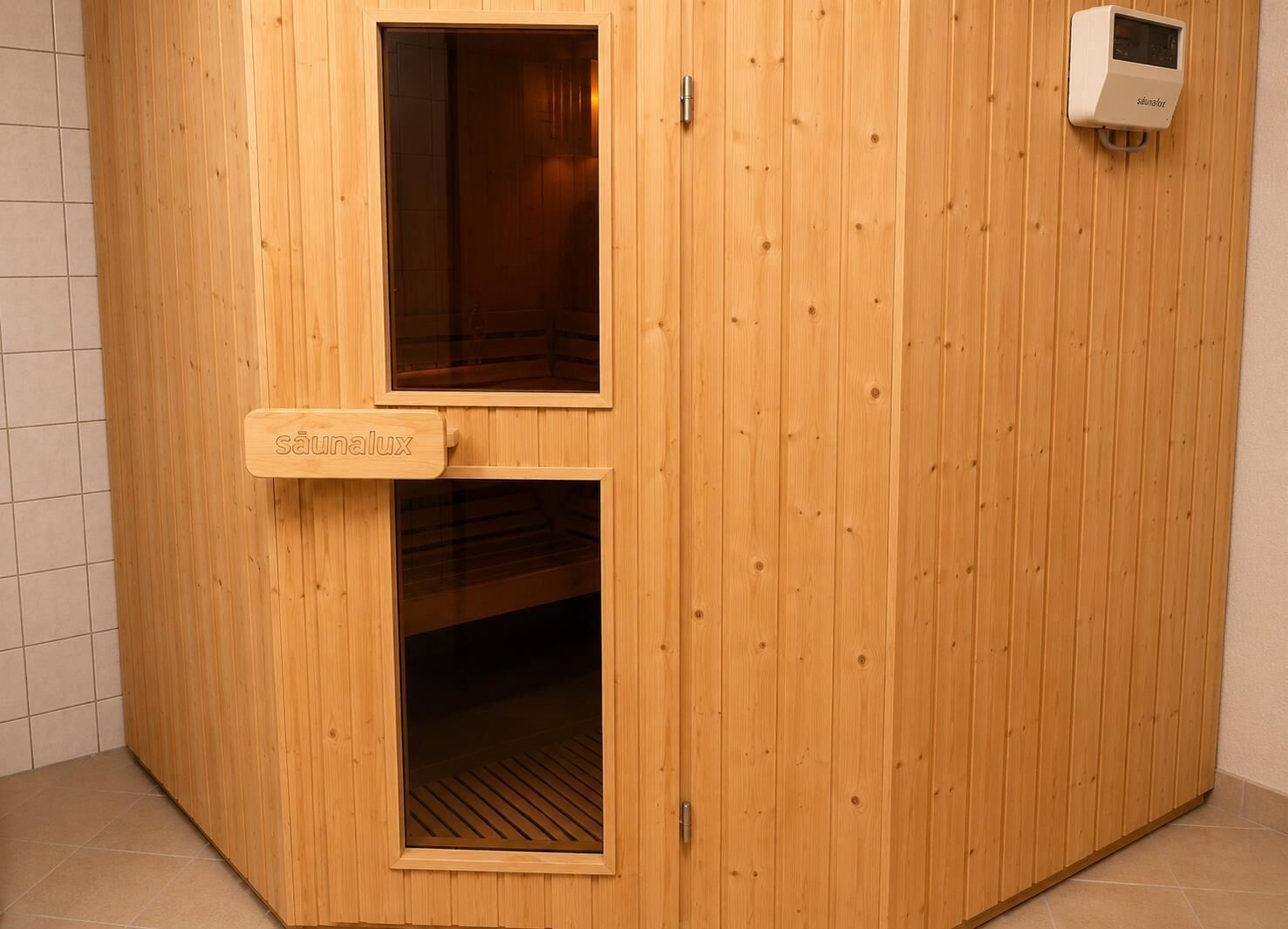 A sauna with wooden walls, a door, and a control panel.