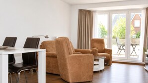 Una sala de estar moderna con comedor, ventanas grandes y vistas al exterior.
