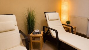 A room with two reclining chairs, a small table with a tissue box, a potted plant, and a wall-mounted lamp. - Haus am Mühlenpark Whg. 14, Steinmarnerstr.77/79, 27476 Cuxhaven (Cuxhaven- Döse)