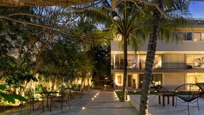 A modern building with a balcony, outdoor seating, and a pathway leading to the entrance. - Caseiba Peaceful Stays 2 (Mérida)