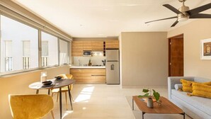 A modern living room with a sofa, coffee table, and a dining area with chairs and a table. - Caseiba Peaceful Stays 2 (Mérida)