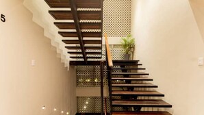 A modern staircase with a wooden finish and metal railings, leading to a landing with a potted plant. - Caseiba Peaceful Stays 2 (Mérida)