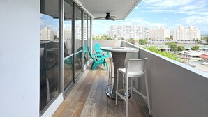 Uma varanda com ventilador de teto, mesa e cadeiras, e vista para a cidade.