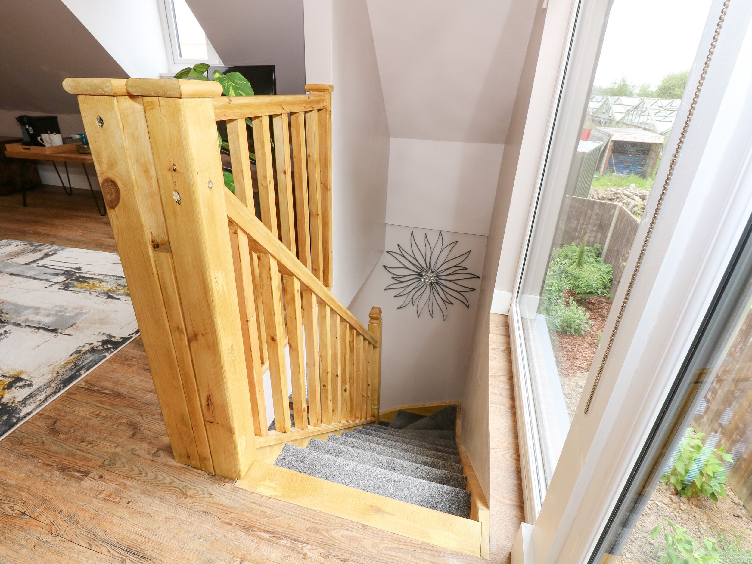 A wooden staircase with a handrail, carpeted steps, and a decorative wall art piece.