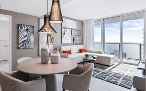 A modern living room with a round table, two chairs, a sofa, and a balcony with a view of the sea. - Luxury Apartment  in Hollywood Beach (Hollywood)