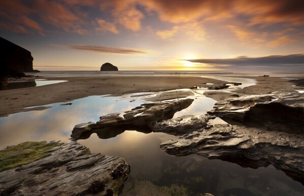 Experience the serene coastal landscape with a prominent rock formation and distant island views.