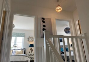 Stylish room with a patterned headboard, bedside lamp, and decorative wall piece, featuring a staircase leading to an upper level.