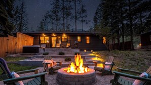 Un hogar circular rodeado de sillas Adirondack, una terraza de madera y una casa con porche.