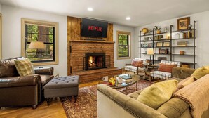 Un salón con chimenea, el logo de Netflix, una estantería y un rincón de estar acogedor.