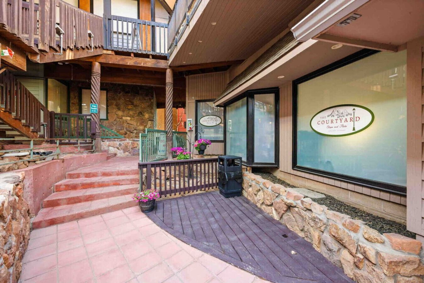 A courtyard with a stone wall, wooden deck, and a sign for 'The Courtyard'.