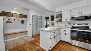 Una cocina con armarios blancos, un microondas integrado y un horno de acero inoxidable.