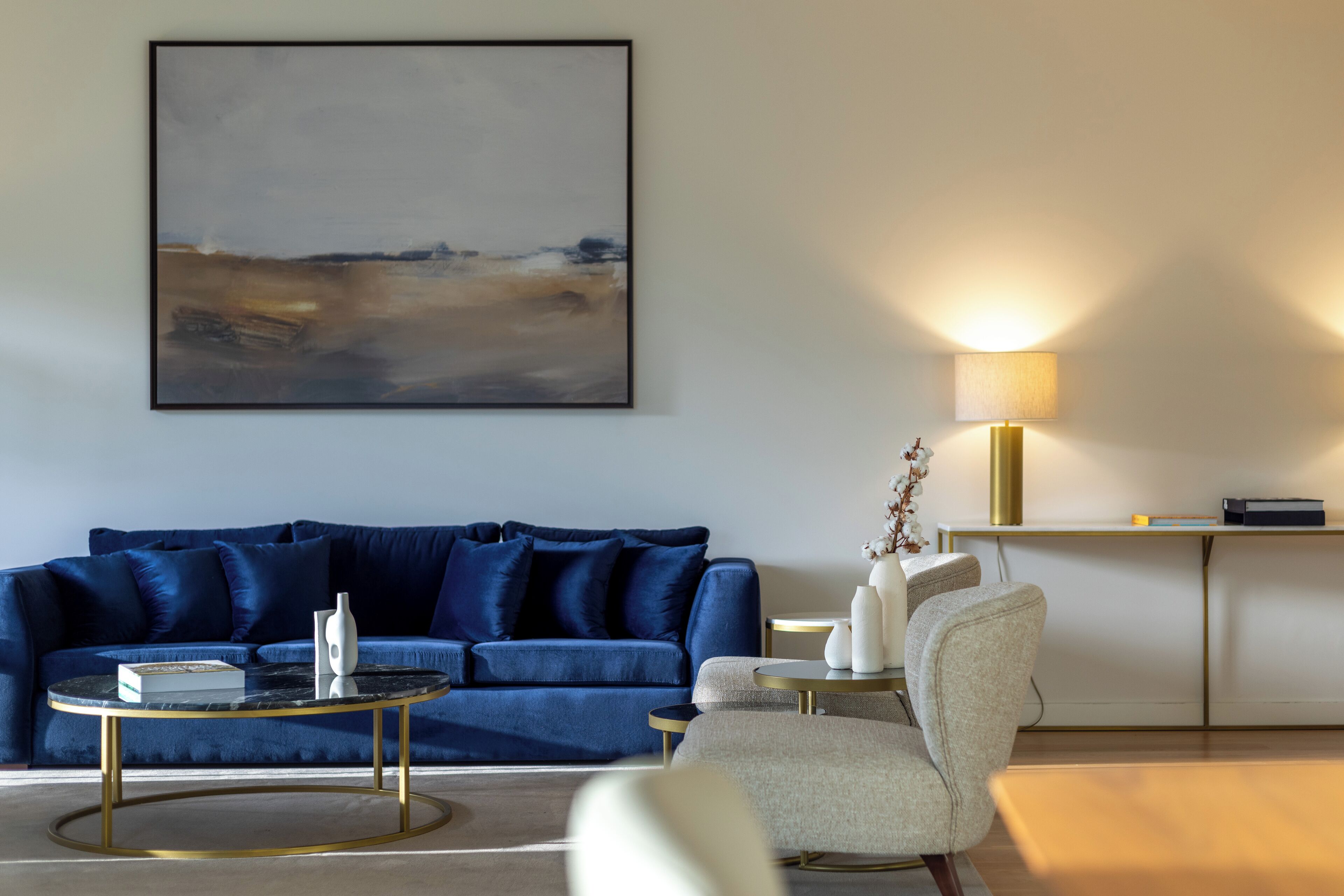 Un salon moderne avec un canapé bleu, une table basse ronde et une lampe.