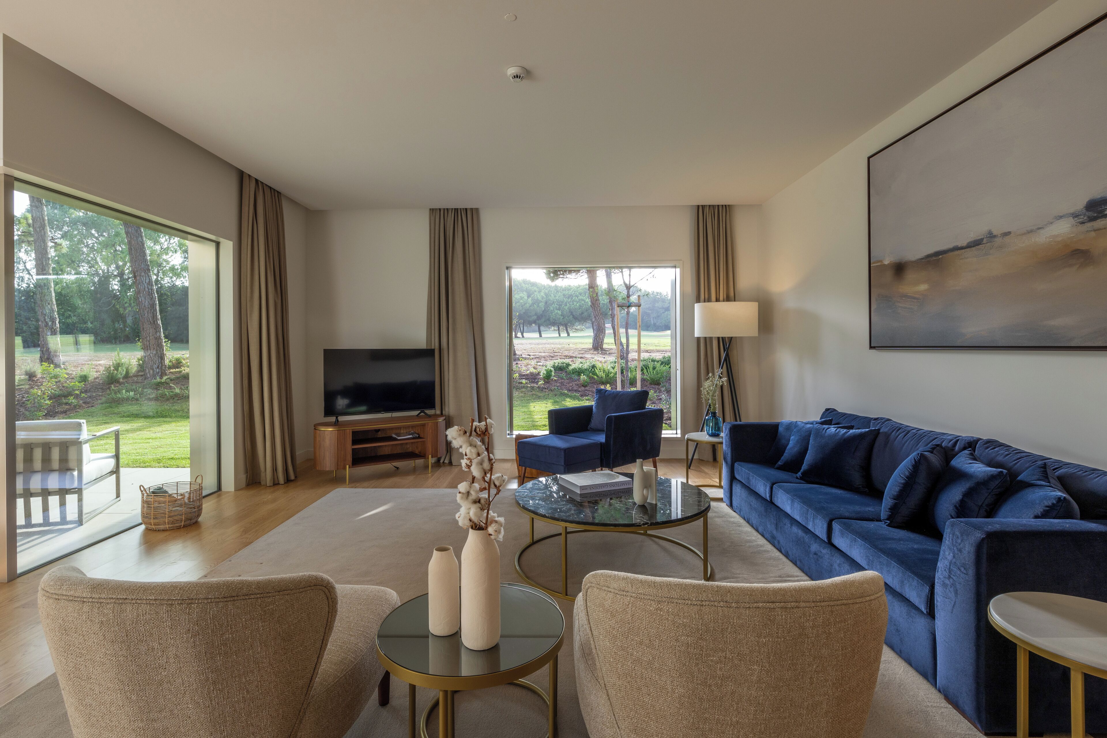 A modern living room with a large TV, comfortable seating, and a view of the outdoors.