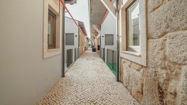 A corridor with stone walls, metal railings, and tiled flooring. - Mezzanine Stylish Apartment Q by Vacationy (Porto)