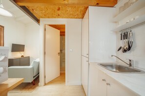 Una cocina moderna con armarios blancos, un lavamanos de acero inoxidable y techo de madera.