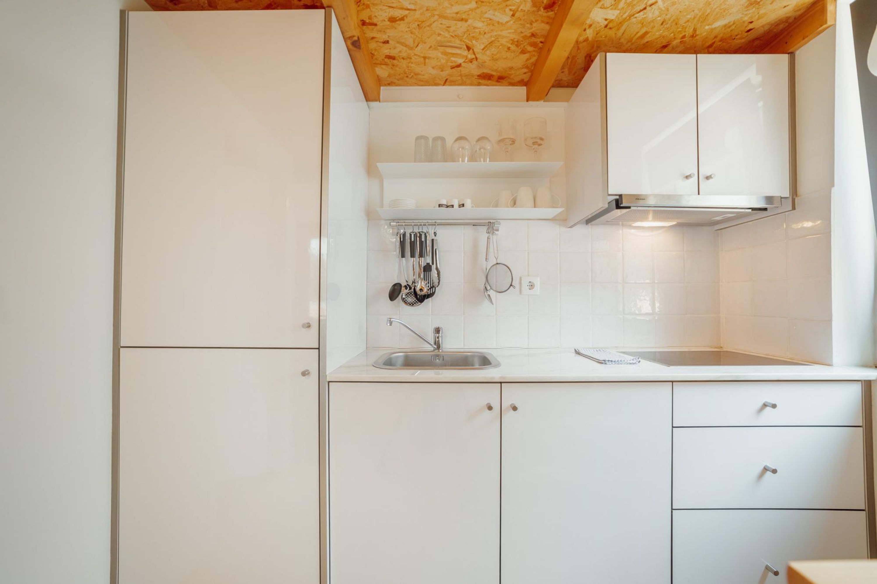 A kitchen with white cabinets, a stainless steel sink, and a wooden ceiling.