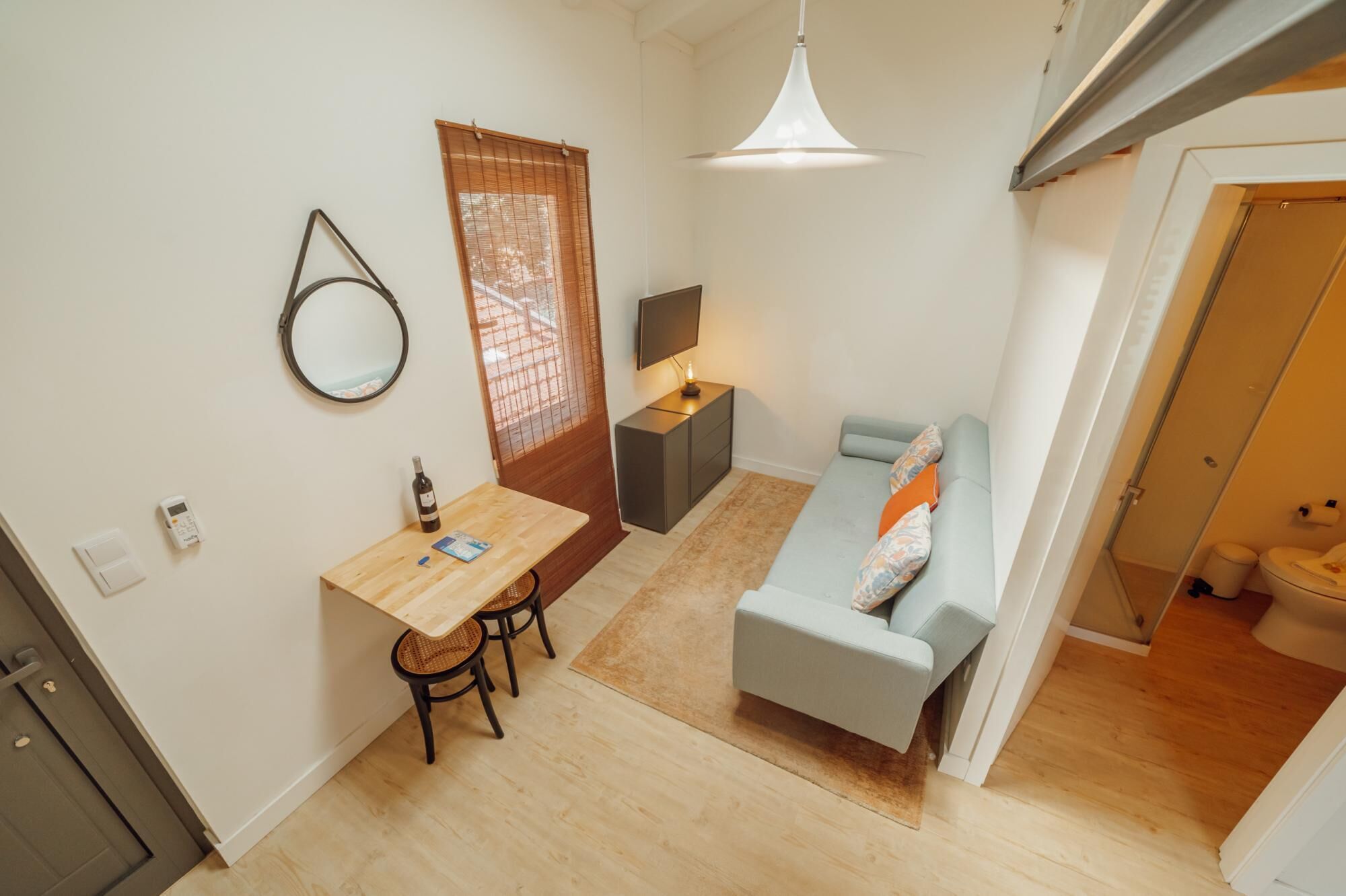 En kompakt opholdsstue med spiseplads, sofa, tv og et træbord.