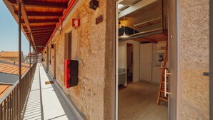 A balcony with a wooden railing, a stone wall, and a red fire extinguisher. - Mezzanine Stylish Apartment Q by Vacationy (Porto)
